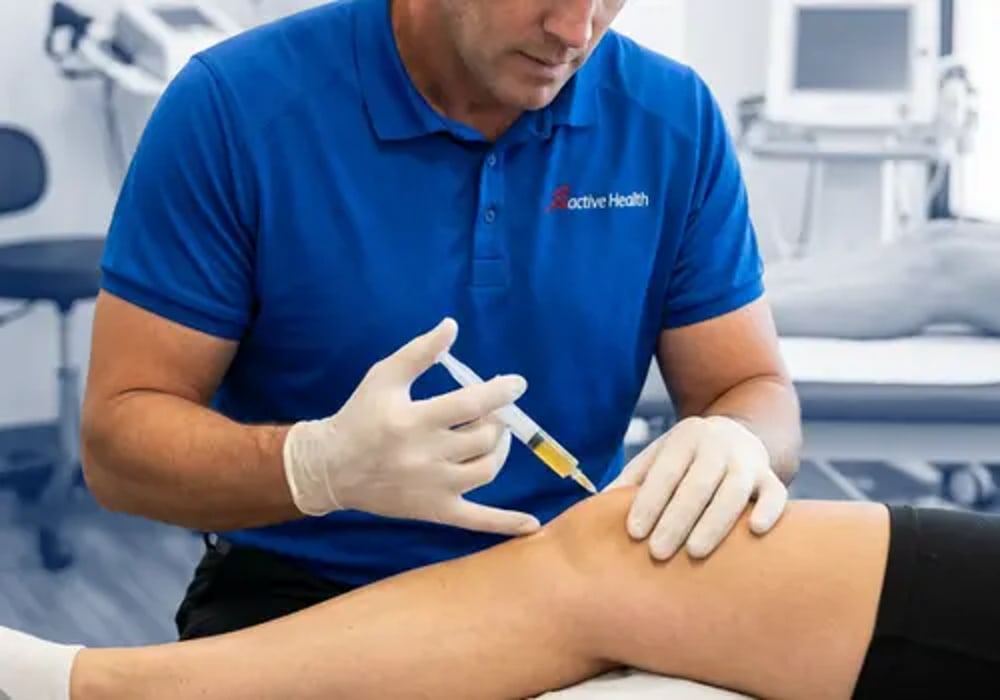 Active Health clinician preparing a guided injection at a patient's knee in the treatment room