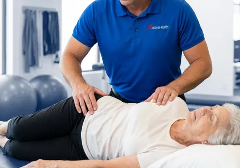 Active Health clinician performing hands-on soft tissue work on a patient on the treatment table